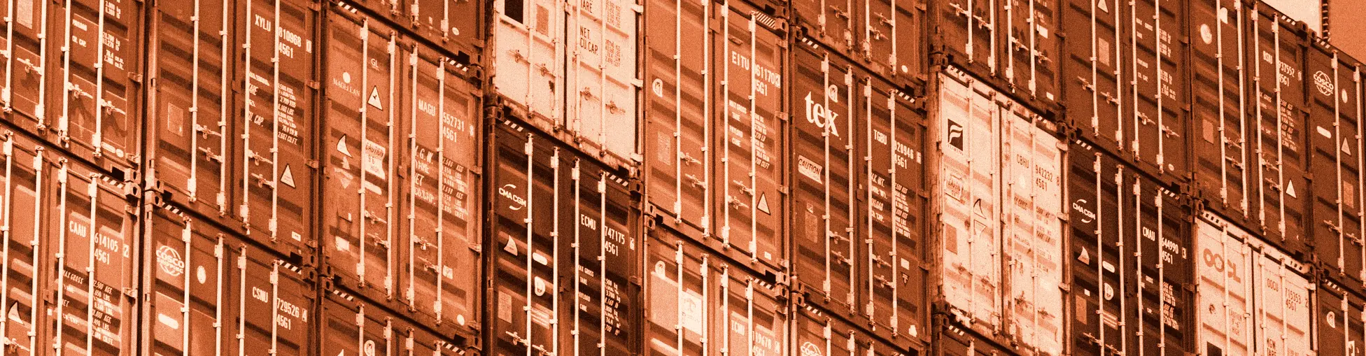 A wall of stacked shipping containers in red, blue, white and green.
